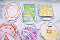 Load image into Gallery viewer, Colorful paper plates with cut-out food shapes on a marble surface