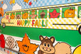 Load image into Gallery viewer, horizontal happy fall classroom banner that you get printed at Walgreens and the bus has happy fall icons peeking out of the window such as a leaf, scarecrow, acorn, and gingham apples.