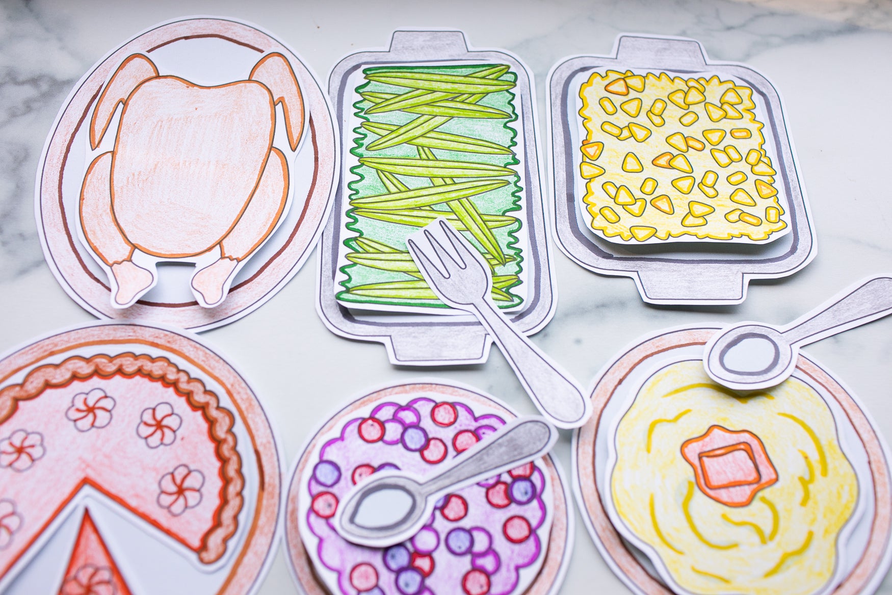 Colorful paper plates with cut-out food shapes on a marble surface