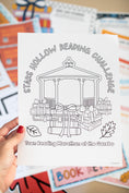 Load image into Gallery viewer, Coloring sheet for 'Stars Hollow Reading Challenge' held by a hand with colorful background
