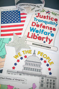Load image into Gallery viewer, Educational materials about the Constitution on a table with an American flag and star.
