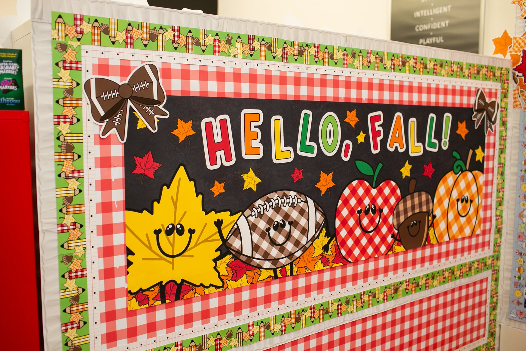 hello fall in primary colors walgreens classroom horizontal banner with a pumpkin, acorn, acorn, pumpkin, football and leaf on it with gingham details on a black background. 