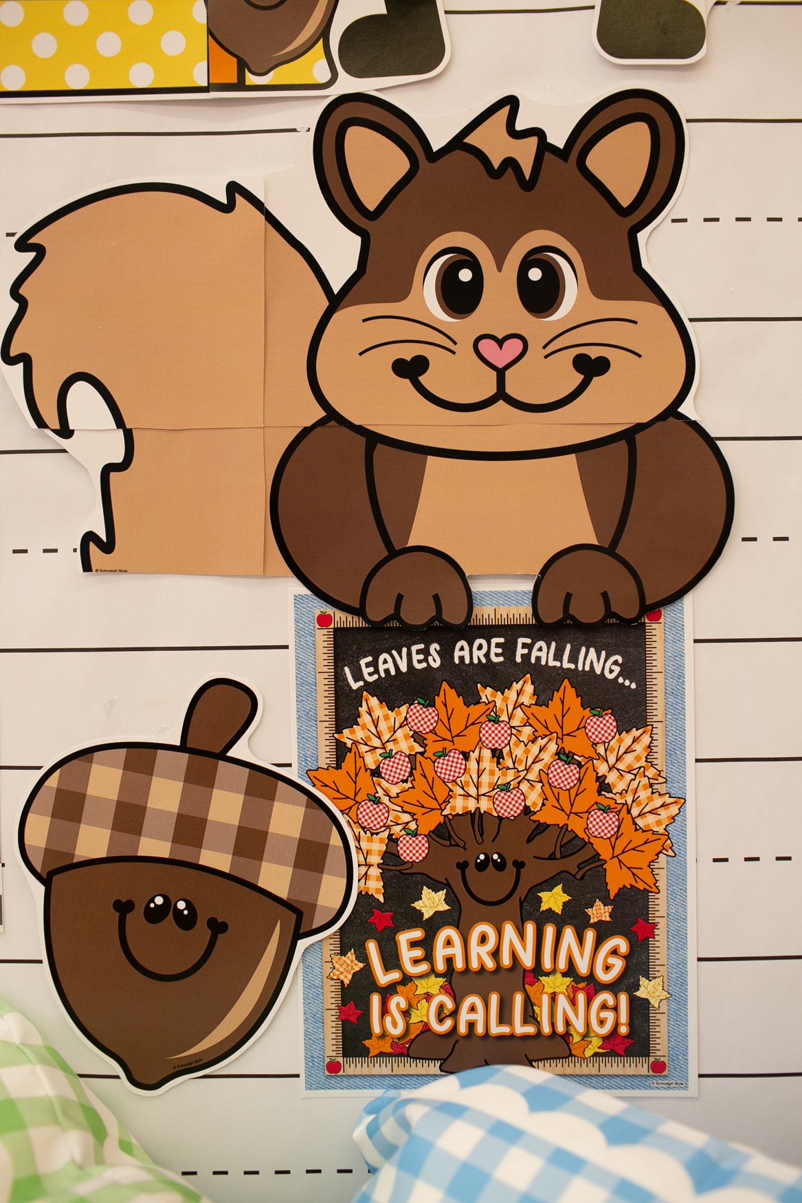 A fall-themed paper craft or decoration featuring a cartoon squirrel, an acorn, and a small autumn message card that reads 'LEAVES ARE FALLING.