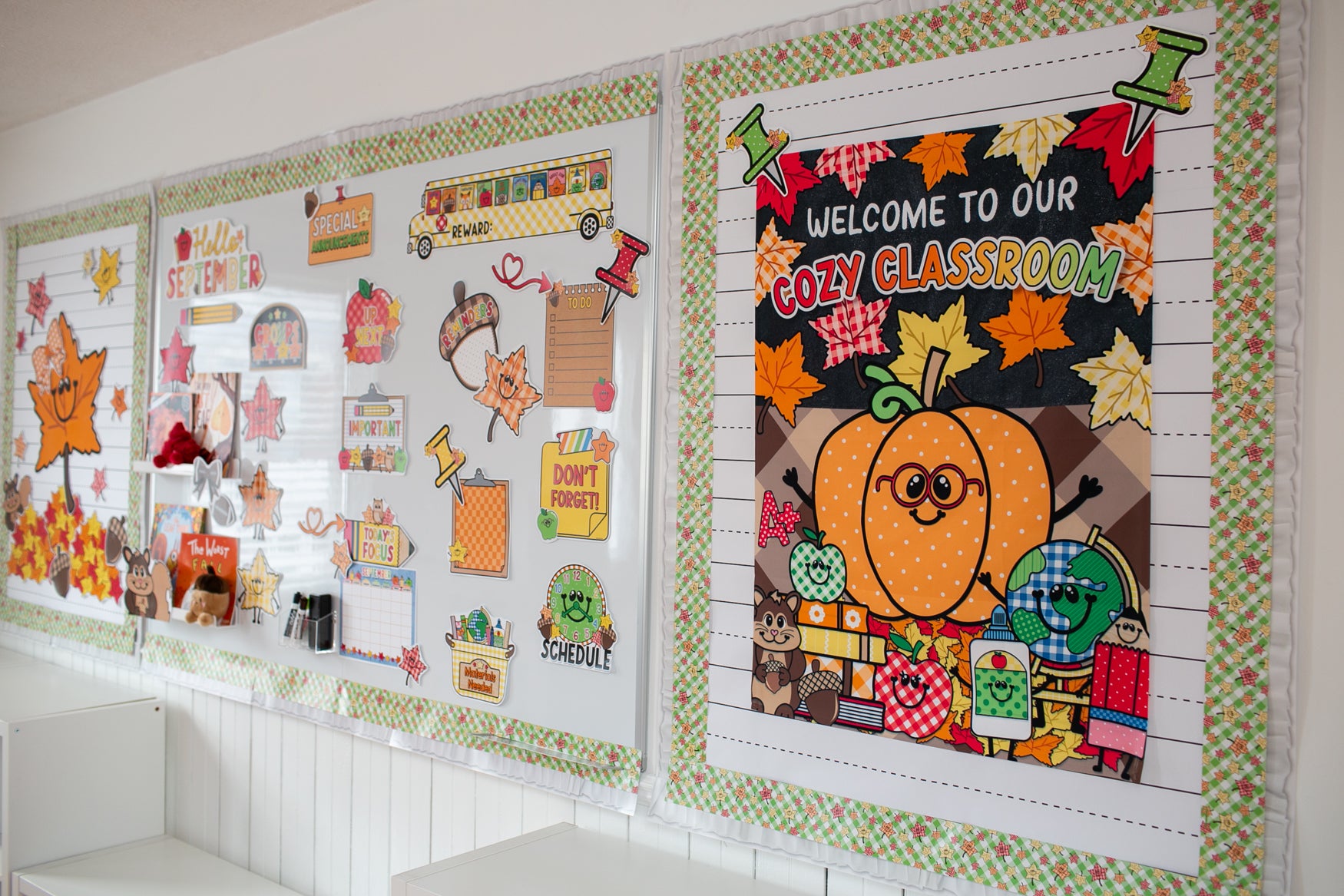 A decorated autumn-themed classroom display board on a white wall, featuring colorful fall illustrations, a pumpkin graphic, leaves, and school-themed decorations.